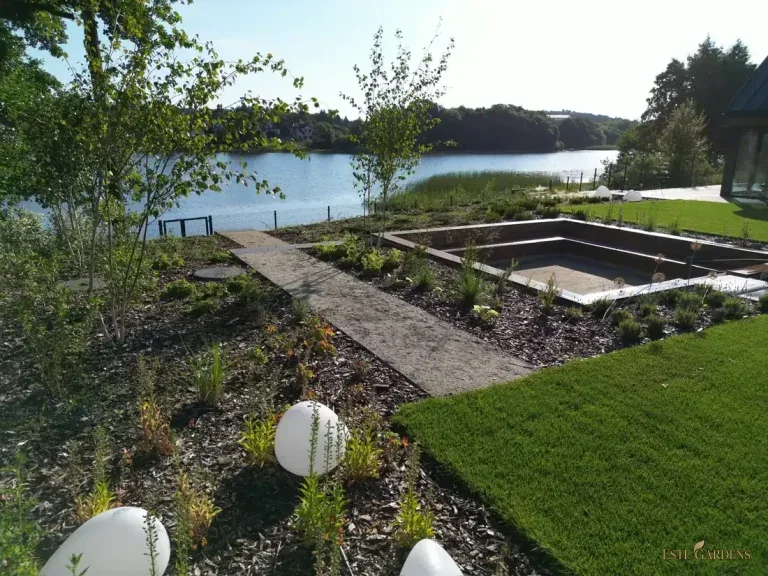 Naturalistyczny ogród nad jeziorem z kamienną ścieżką w Gdańsku Osowej